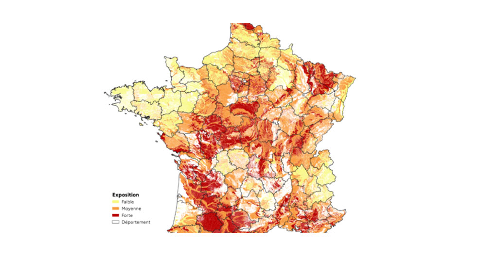 Tablette affichant la carte BRGM georisques.gouv.fr avec zones colorées d'aléa retrait-gonflement des argiles sur une commune française, main pointant une zone spécifique sur l'écran tactile